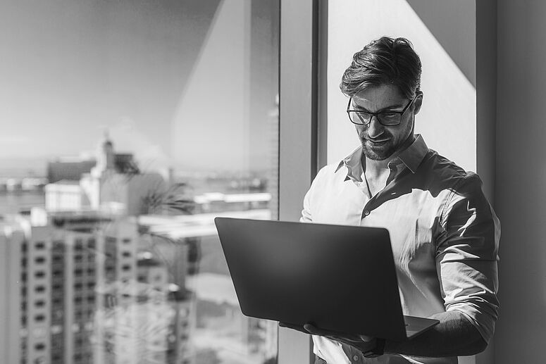 Mann mit PC auf dem Balkon 